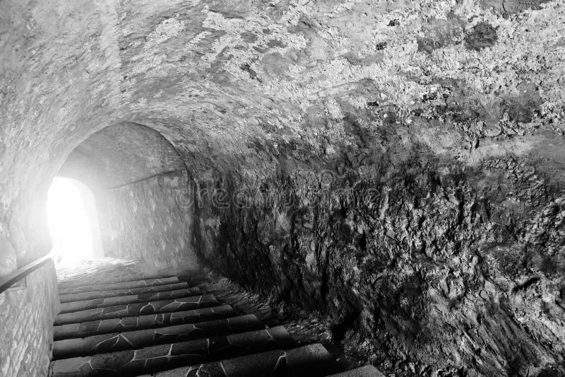 Stone cave with a light at the end of the tunnel. Scary black an stock images Stone cave with a light at the end of the tunnel. Scary black an stock images