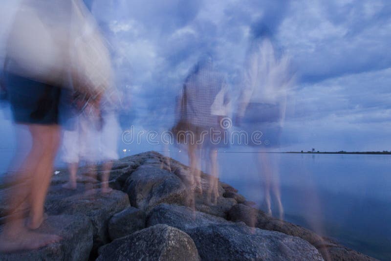 Stone Pier at the Beach with People Hiking on it during an Evening, Long Exposure Stock Image
