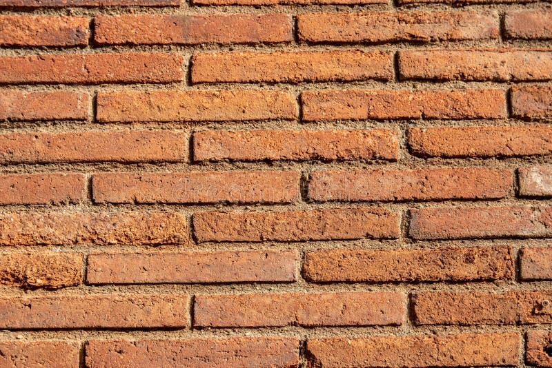 Stone texture background. Closeup of a old red brown of a weathered brick wall texture with a hilly uneven surface. Abstract