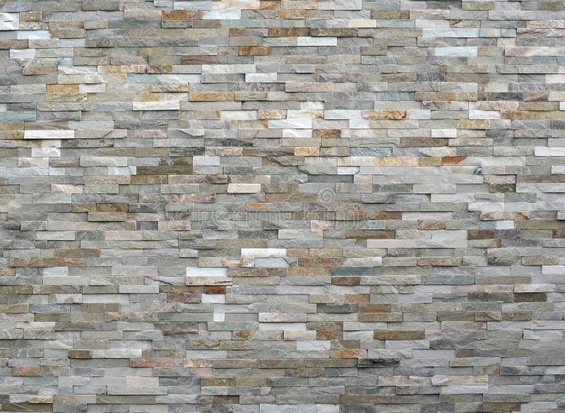 Stone wall cladding made of stacked stripes rocks. The colors are from white to gray and brown.