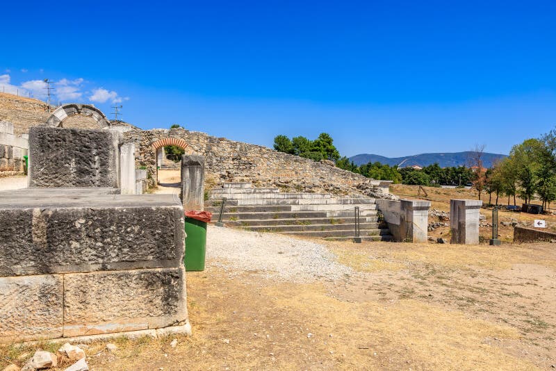 A stone wall with a green trash can in front of it. Ruins of the ancient city of Philippi, Greece royalty free stock photography