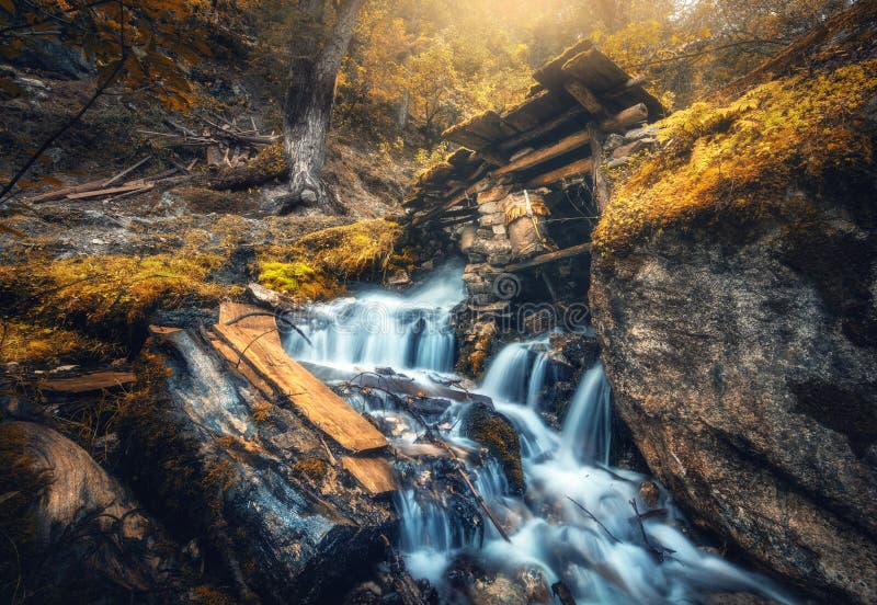 Stony well in colorful orange forest with little waterfall