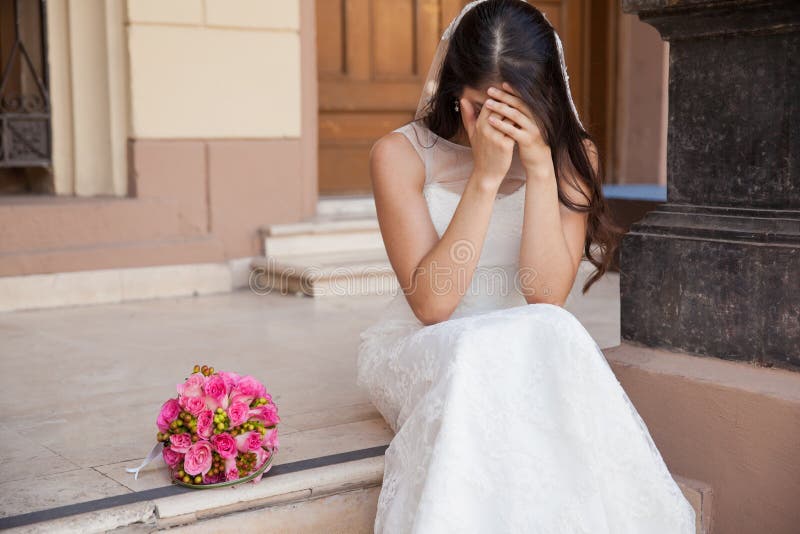 Hopeless bride crying outside a church after being stood up on her wedding day. Hopeless bride crying outside a church after being stood up on her wedding day