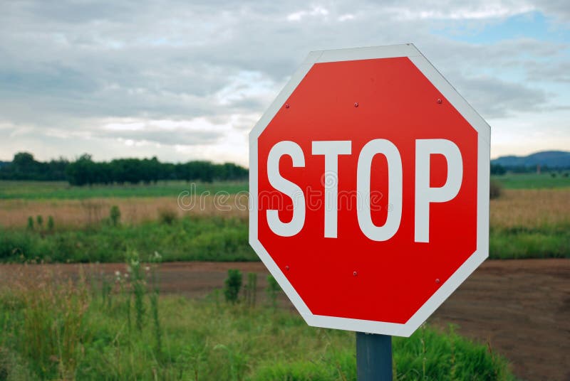 Immagine di un segnale di stop rosso contro strada di campagna, paesaggio.