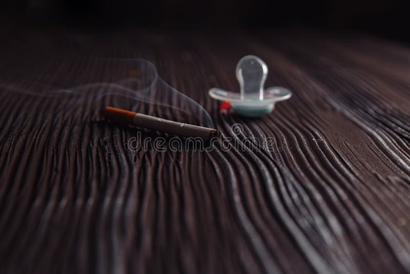 Stop smoking concept. Cigarette and baby pacifier on a wooden table