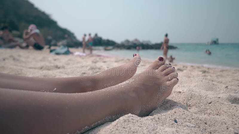 Stopy z manicure na piaszczystej plaży z bliskim widokiem