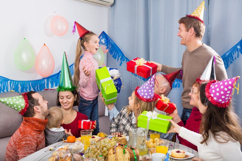 Stor familj som räcker gåvor till födelsedagflickan royaltyfri foto Stor familj som räcker gåvor till födelsedagflickan royaltyfri foto