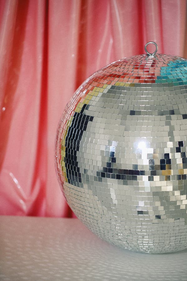 Stor glansig reflekterande spegel silverkungande nattlig discoball mot färgstark bakgrund som reflekterar ljusa vertikalt royaltyfri fotografi