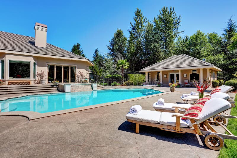 Great backyard with swimming pool and lounge chairs in American Suburban luxury house. Northwest, USA. Great backyard with swimming pool and lounge chairs in American Suburban luxury house. Northwest, USA