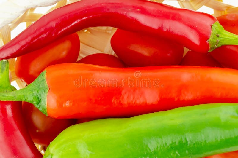 Stora fröskidor av glödhet peppar per stycke av en lång grön grönsak i en tomatkorgnärbild arkivbilder Stora fröskidor av glödhet peppar per stycke av en lång grön grönsak i en tomatkorgnärbild arkivbilder