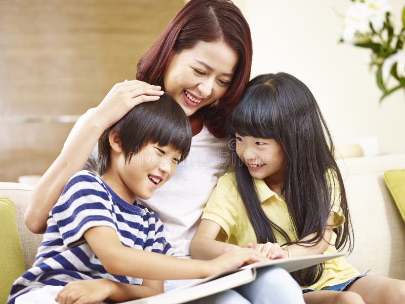 Storia asiatica della lettura della madre a due bambini immagini stock Storia asiatica della lettura della madre a due bambini immagini stock