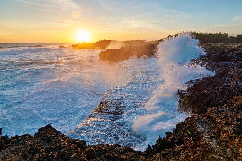 Assalto delle Onde del Mare che si Infrangevano sulla battigia della spiaggia di Nusa Lembongan, Indonesia, al Tramonto.