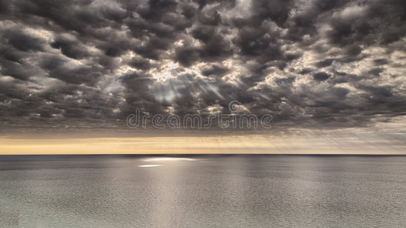 Stormy dramatic clouds and sun rays over a lake