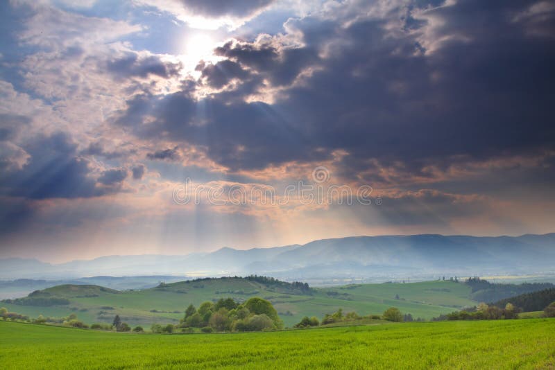 Krajina, temné bouřlivé mraky a slunečné paprsky.