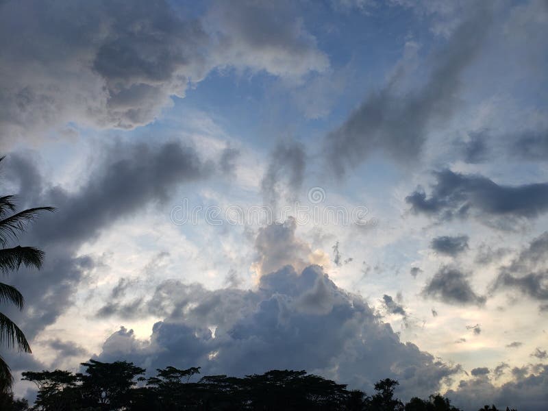 Stormy Sky with a Patch of Blue and a Few Silhouetted Trees royalty free stock photo