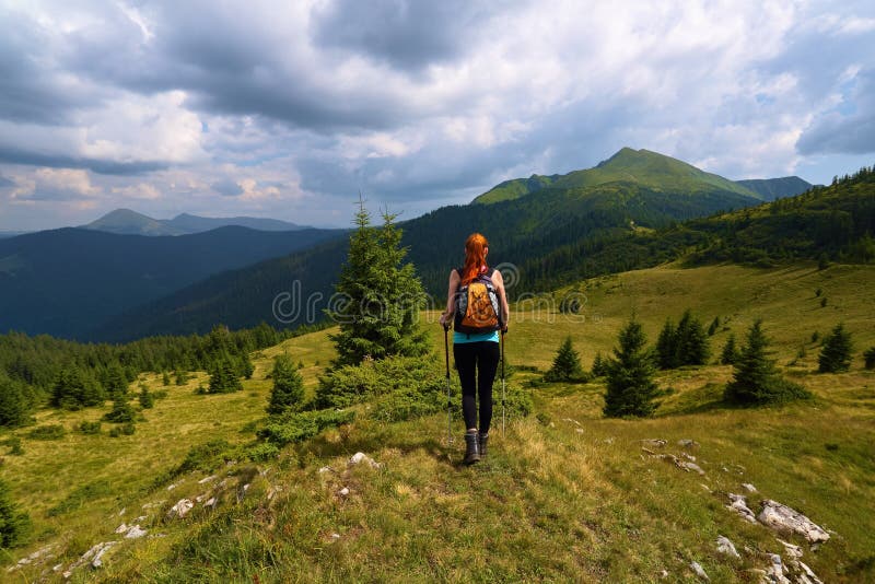 Stormy, thundery sky. The view with the peaks of mountain. Sporty red hair girl climbs up to the hill with rocks. Extreme sport. stock images Stormy, thundery sky. The view with the peaks of mountain. Sporty red hair girl climbs up to the hill with rocks. Extreme sport. stock images