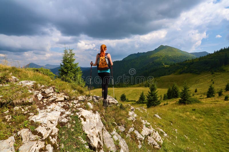 Stormy, thundery sky. The view with the peaks of mountain. Sporty red hair girl climbs up to the hill with rocks. Extreme sport. royalty free stock photography Stormy, thundery sky. The view with the peaks of mountain. Sporty red hair girl climbs up to the hill with rocks. Extreme sport. royalty free stock photography