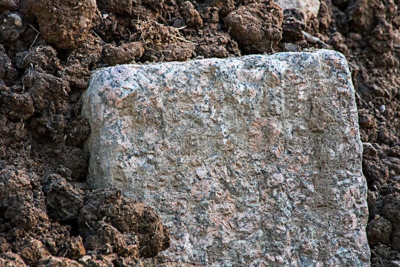 Stort rektangulärt stycke av granit i jordningen arkivfoton