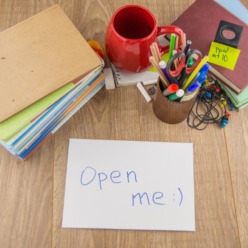 Student desktop, pile of books, accessories, stationery. in the forum is an  envelope bearing the words ` open me. Student desktop, pile of books, accessories, stationery. in the forum is an  envelope bearing the words ` open me