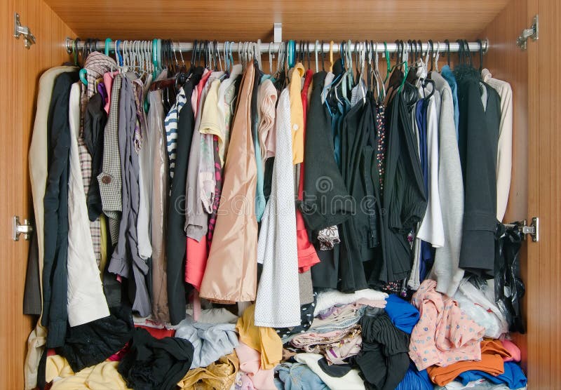 Pile of colorful messy clothes in closet. Untidy cluttered woman wardrobe. Pile of colorful messy clothes in closet. Untidy cluttered woman wardrobe