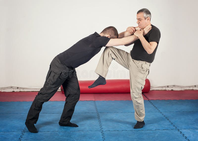 Kapap instructor demonstrates street fighting self defense technique against holds and grabs with his student. Kapap instructor demonstrates street fighting self defense technique against holds and grabs with his student