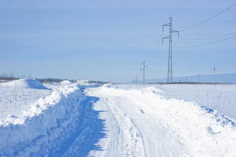 Snow-covered winter road with power line in the field, Russia. Snow-covered winter road with power line in the field, Russia