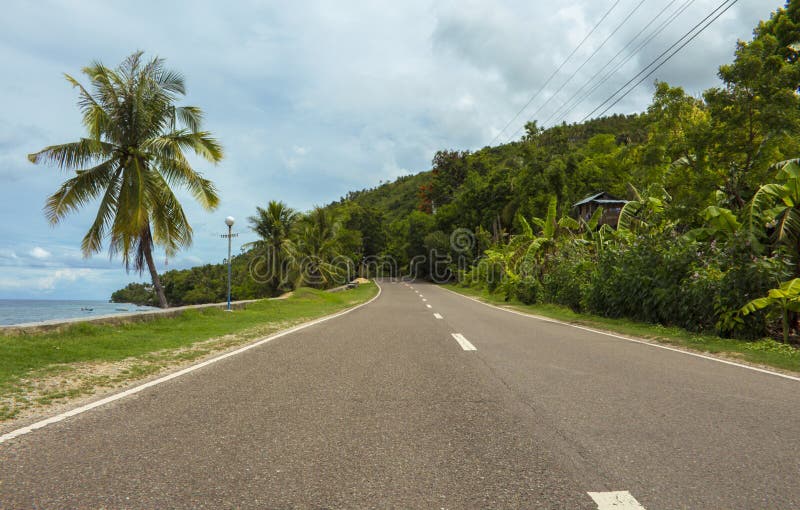 Strada principale sull'isola tropicale Strada costiera nel pomeriggio Strada vuota dalla spiaggia immagine stock Strada principale sull'isola tropicale Strada costiera nel pomeriggio Strada vuota dalla spiaggia immagine stock