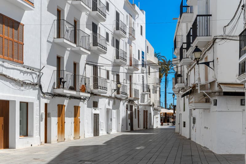Strada stretta con edifici bianchi brillanti sotto il cielo azzurro in Eivissa Ibiza Spagna immagini stock