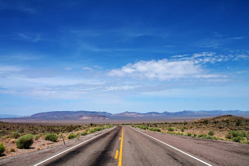Strada vuota del deserto con cielo aperto e le montagne distanti nel Nevada