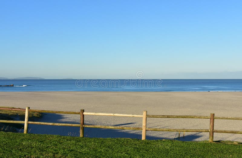 Strand met gras en houten omheining Ochtend lichte, zonnige dag, blauwe hemel Galicië, Coruna, Spanje royalty-vrije stock fotografie Strand met gras en houten omheining Ochtend lichte, zonnige dag, blauwe hemel Galicië, Coruna, Spanje royalty-vrije stock fotografie