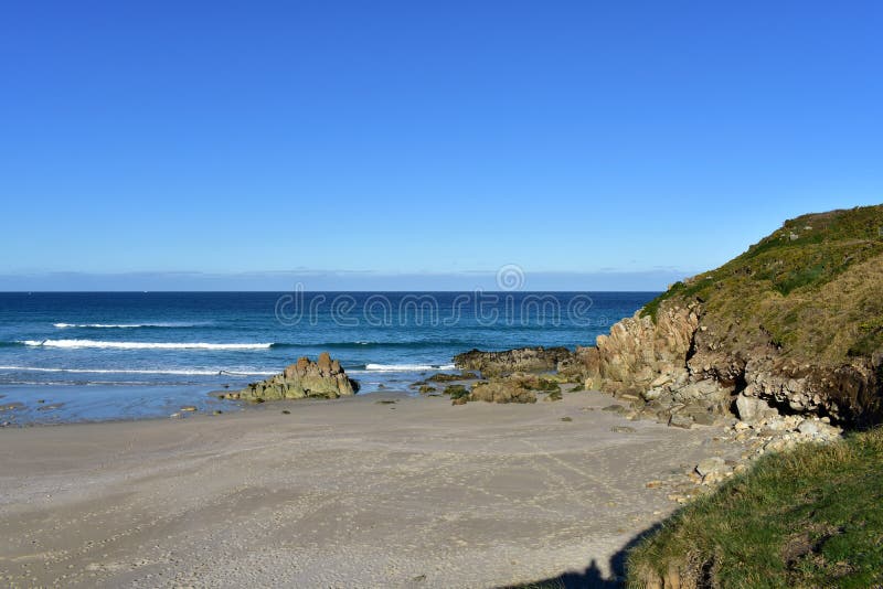 Strand met rotsen, gras en ochtendlicht Blauwe overzees met klein golven en schuim, zonnige dag Galicië, Spanje royalty-vrije stock afbeeldingen Strand met rotsen, gras en ochtendlicht Blauwe overzees met klein golven en schuim, zonnige dag Galicië, Spanje royalty-vrije stock afbeeldingen