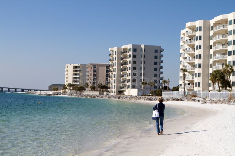 Mature female tourist walks along the beach in front of condominiums at Destin, Florida. Mature female tourist walks along the beach in front of condominiums at Destin, Florida.