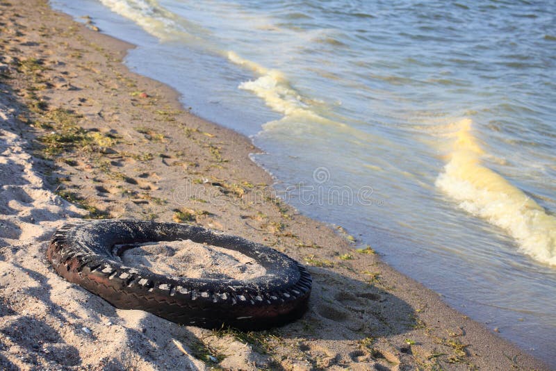 Tire on a beach - ecology environment. Tire on a beach - ecology environment