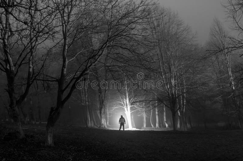 Strange silhouette in a dark spooky forest at night, mystical landscape surreal lights with creepy man royalty free stock photography Strange silhouette in a dark spooky forest at night, mystical landscape surreal lights with creepy man royalty free stock photography