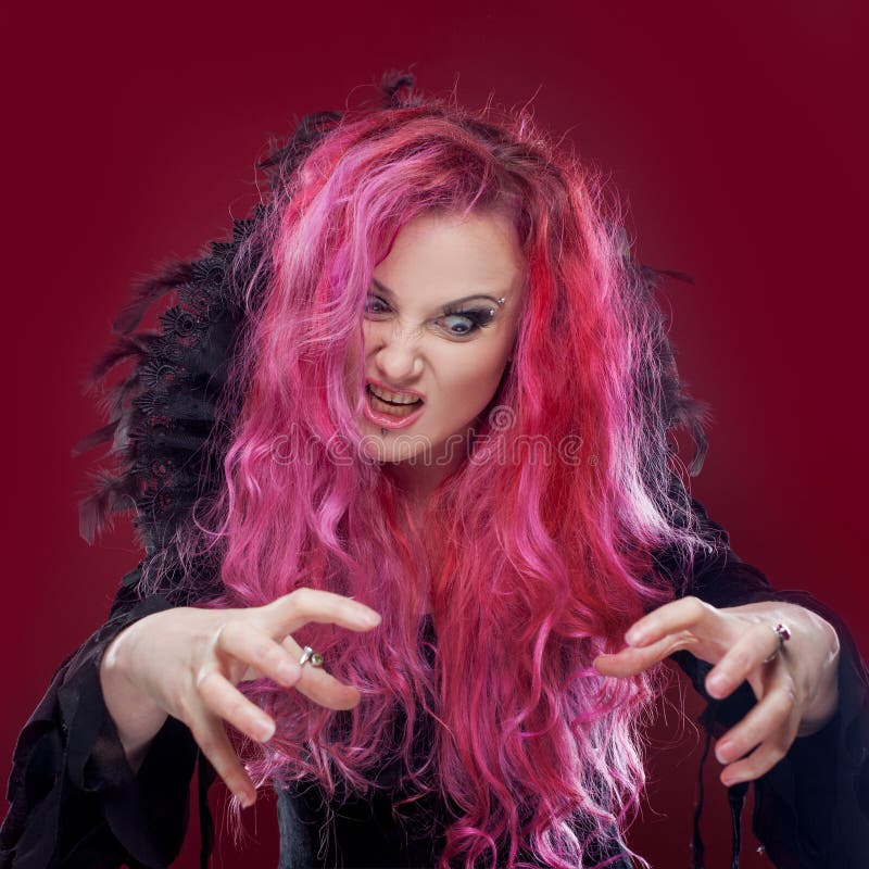 Straszna czarownica z czerwonym włosy wykonuje magię halloween
