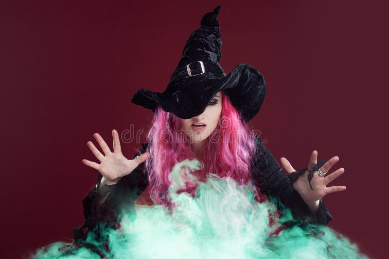 Straszna czarownica z czerwonym włosy wykonuje magię nad zielonym dymem Halloween, horroru temat