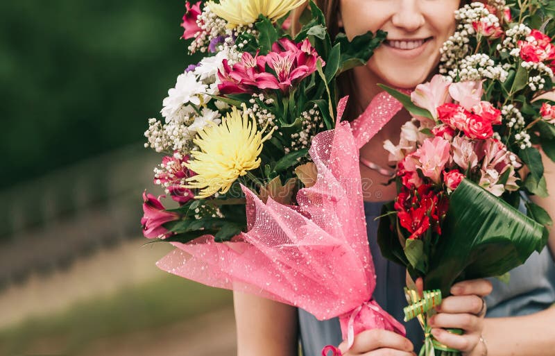Strauß von Blumen in den Händen einer Schönheit lizenzfreie stockbilder