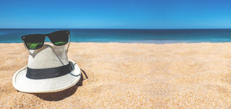 Straw beach Hat and sun glasses placed on the sand beach and sea have a holiday summer relaxing and travel bright sky in thailand