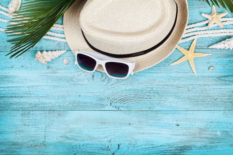 Straw hat, sunglasses, palm leaves, rope, seashell and starfish on blue wooden table top view in flat lay style. Summer holidays. stock photo Straw hat, sunglasses, palm leaves, rope, seashell and starfish on blue wooden table top view in flat lay style. Summer holidays. stock photo