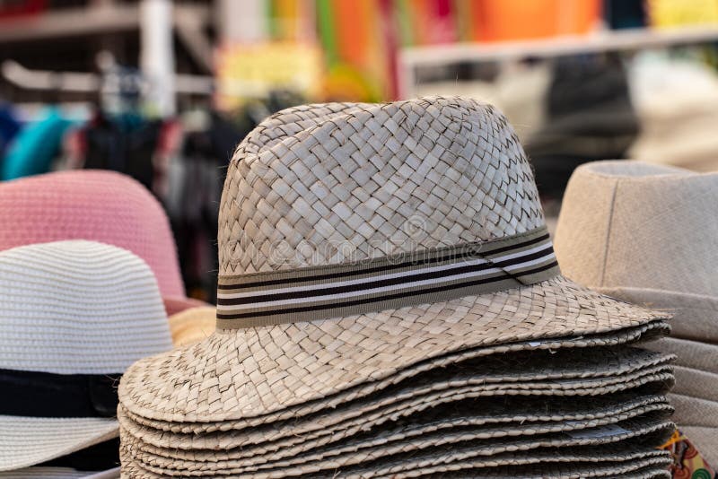Straw hats background. Closeup with selective focus on a stack straw hats for sale with blurred market shop background. Macro stock photos