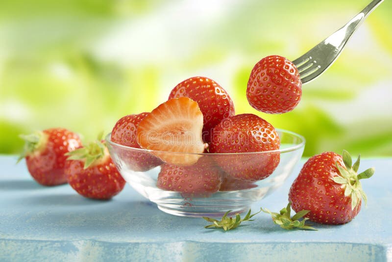 Strawberries served in a glass bowl on a blue table outside