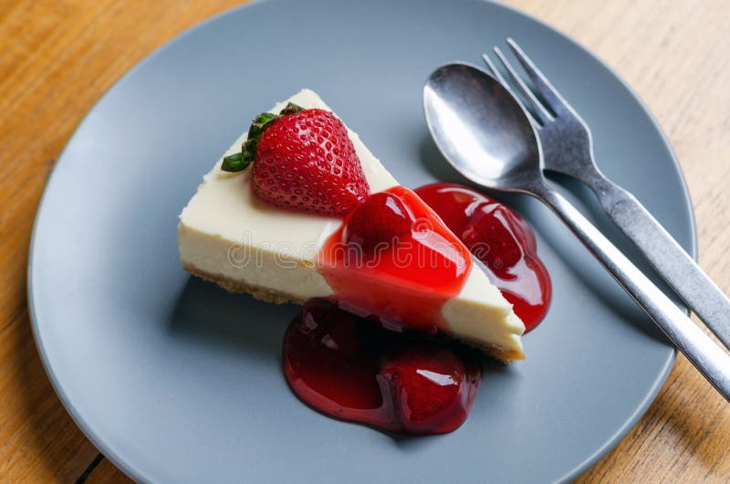 Strawberry Cheesecake with spoon and fork on wooden table