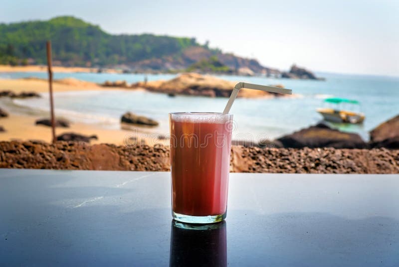 Strawberry cocktail with a straw in a glass stands on the table on background of sea.