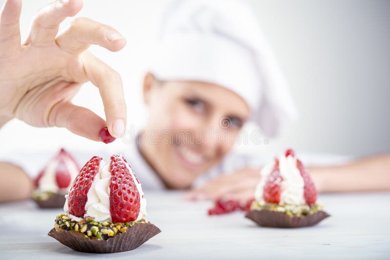 Strawberry cupcakes in the foreground, blurred background chef woman