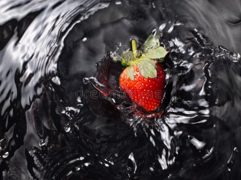 Strawberry entering the water on black background stock photos Strawberry entering the water on black background stock photos