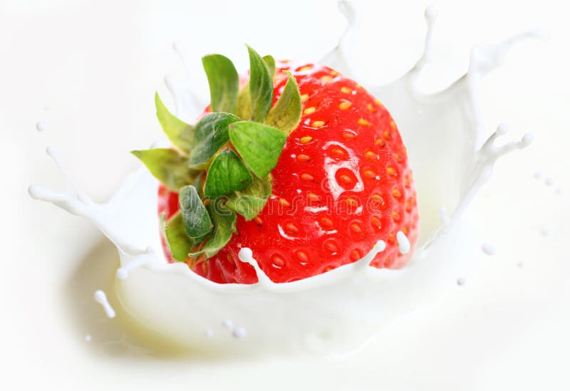 Strawberry falling into milk stock image