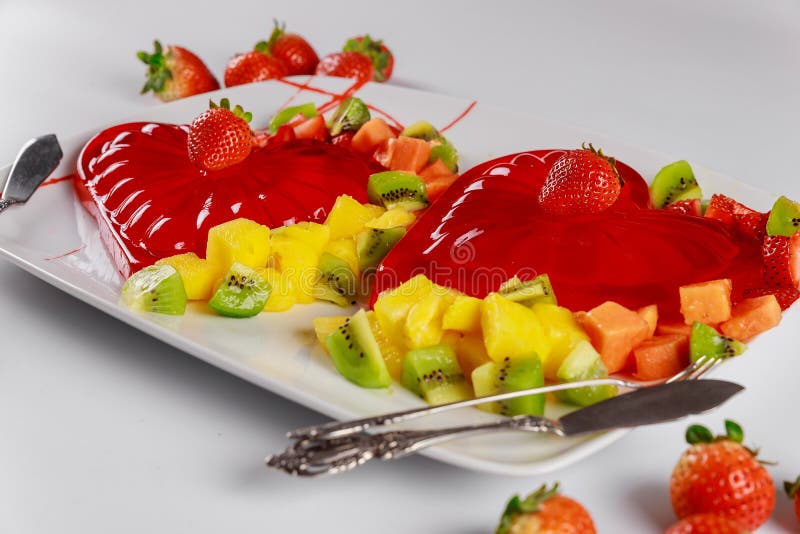 Strawberry gelatin decorated with fresh strawberry, kiwi and pineapple. Dessert for couple