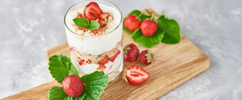 Strawberry granola or smoothie in glass and fresh berries on a cutting board, long banner. Healthy breakfast