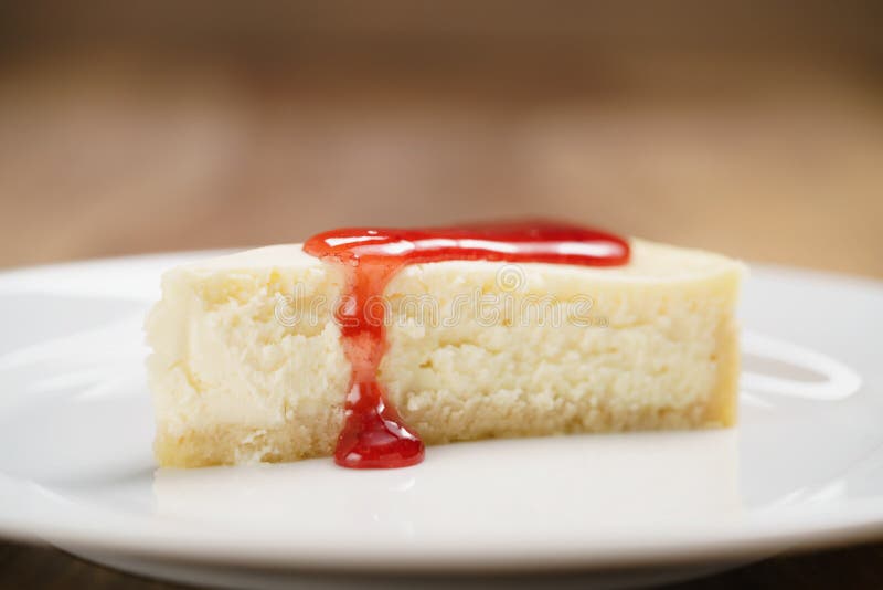Strawberry Jam Pour on Cheesecake on Plate on Wood Table Stock Photo