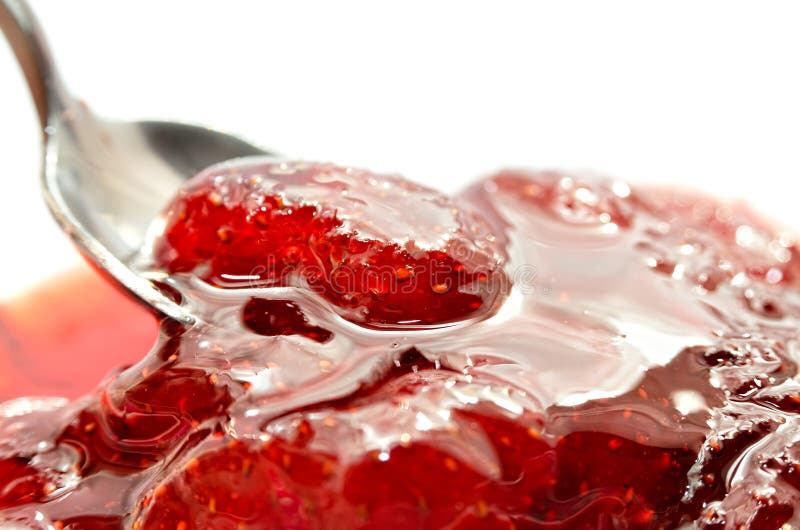 Strawberry jam is stirred with a spoon on a white background. Fruit dessert close up. Confectionery